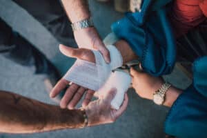 man bandaging injured car accident victim's hand