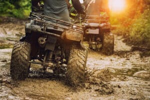 ATV riders driving through a muddy path